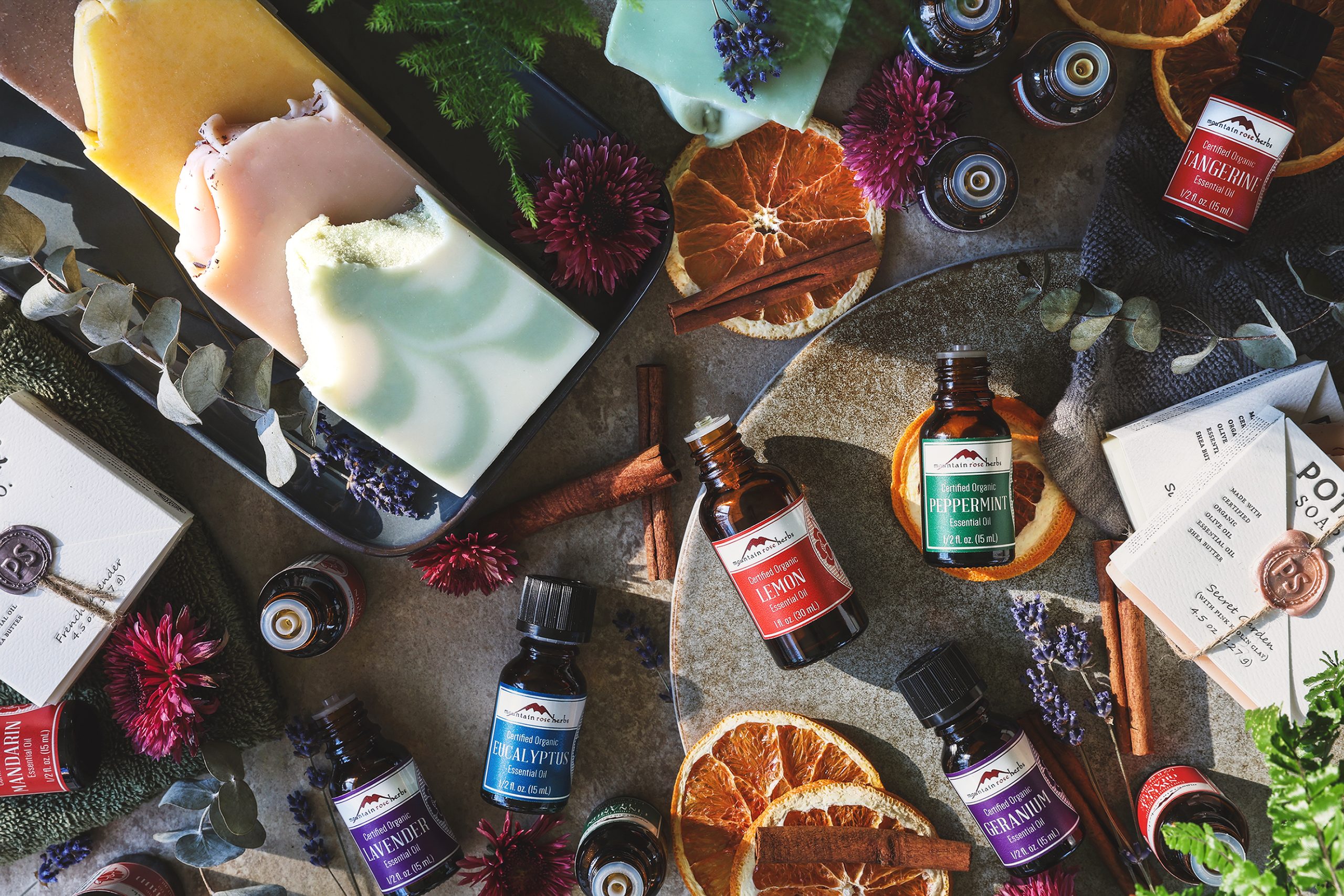 An overhead photo of various essential oils and bars of handmade soap